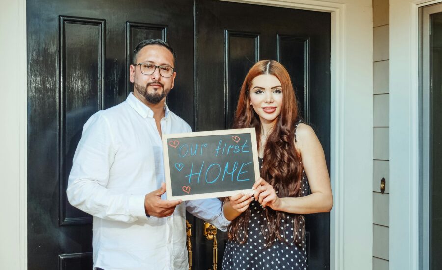 New homeowners in Georgia holding a chalkboard sign saying 'our first home'
