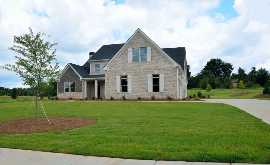 Modern new construction brick home in Georgia with manicured lawn and long driveway